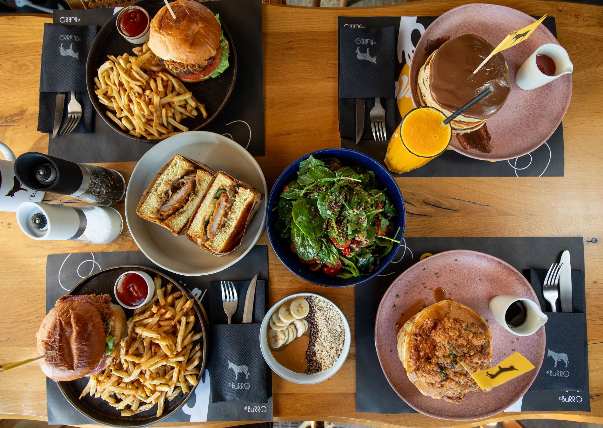 Τραπέζι brunch από ψηλά: burgers, sando, pancakes, σαλάτες και φρέσκος χυμός
